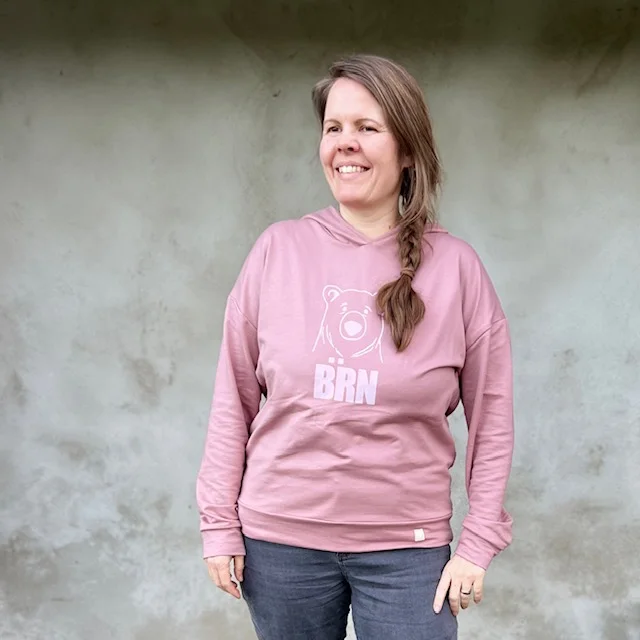 Romi in einem altrosa Hoodie mit weissem Bärenkopf und Bärn-Schriftzug
