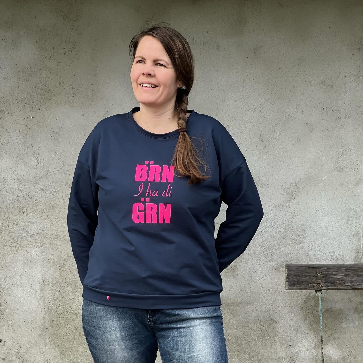 Romi in einem dunkelblauen Pullover mit pinkem Bärn-i-ha-di-gärn-Motiv